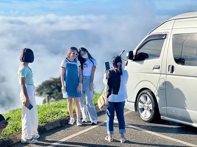 ลูกค้าถ่ายรูปที่จุดชมวิวทะเลหมอกข้างรถตู้ที่เช่าในเชียงราย